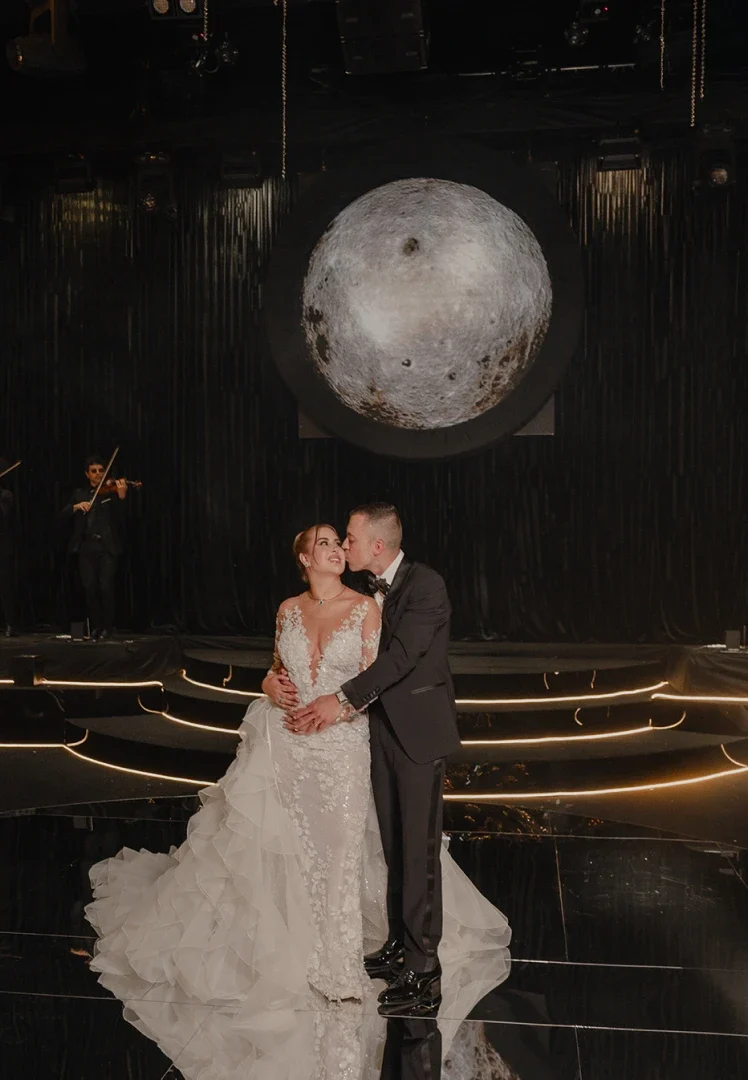 Pareja de esposos posando frente a una figura grande de la luna