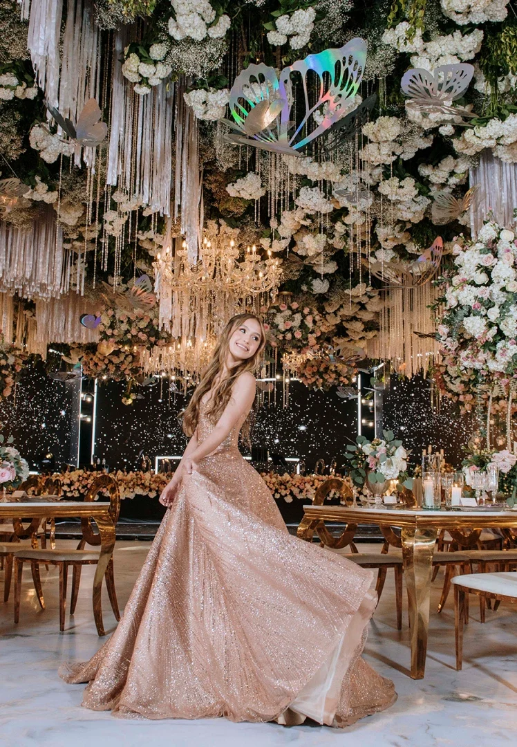 Chica feliz en salón elegante con arreglos florales y candelabros en el techo